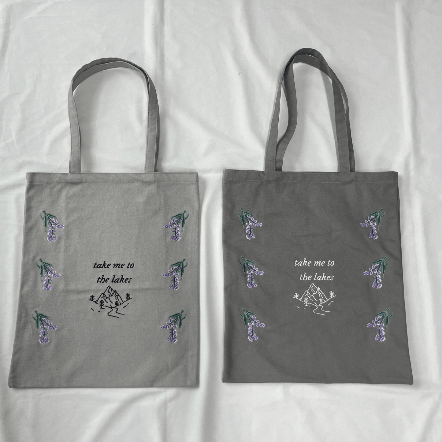 Two gray tote bags with floral designs and text on a white background