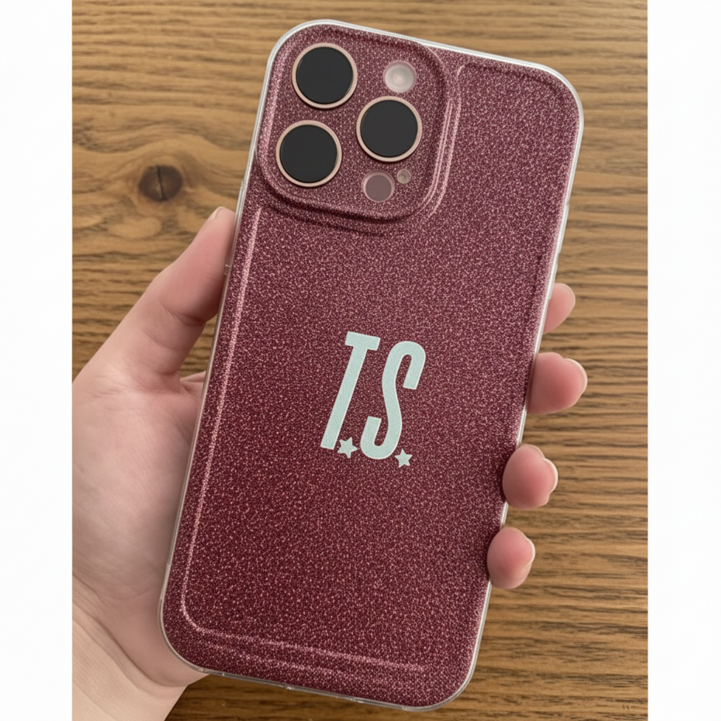 Phone case with 'T.S.' initials held by a hand on a wooden surface