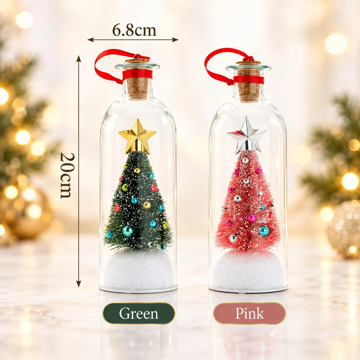 Two small Christmas tree glass bottle ornaments shown side by side on a marble surface with blurred holiday lights in the background. The left one is labeled Green and contains a miniature green Christmas tree with colorful ornaments and a gold star.