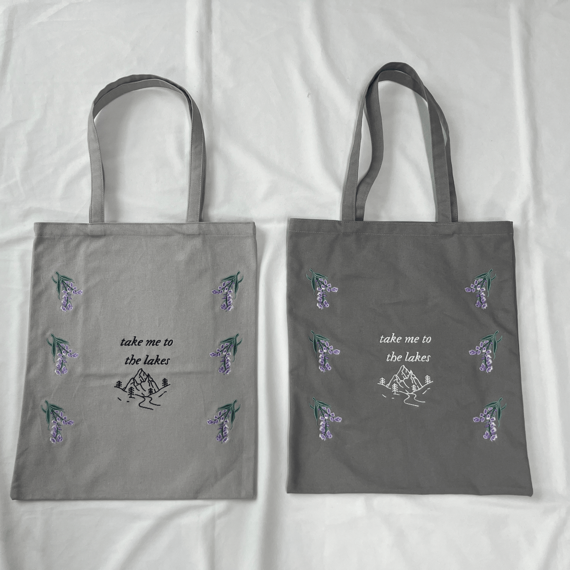 Two gray tote bags with floral designs and text on a white background