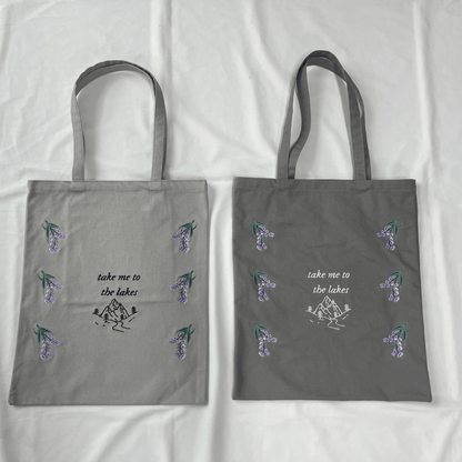 Two gray tote bags with floral designs and text on a white background