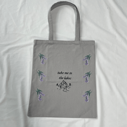 Gray tote bag with floral designs and text on a white background