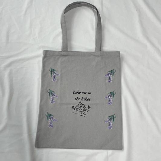 Gray tote bag with floral designs and text on a white background