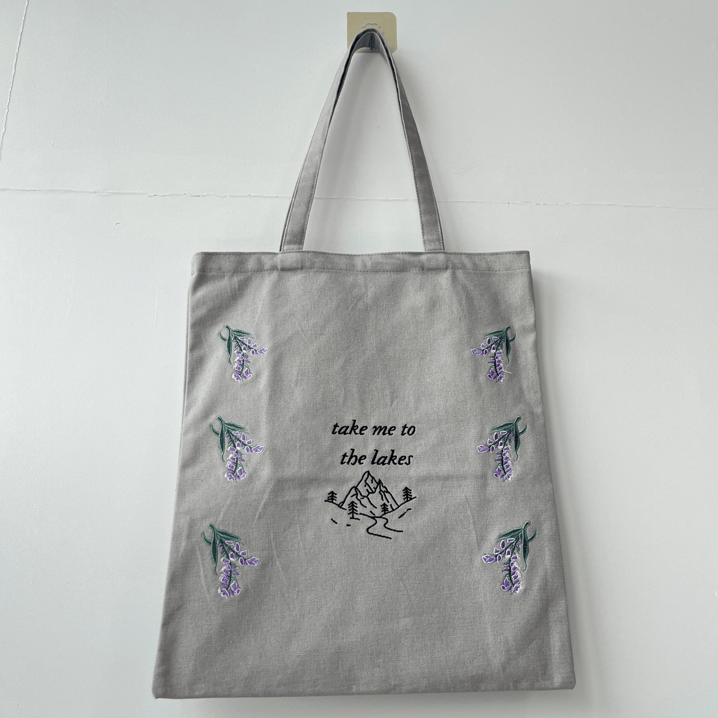 Gray tote bag with nature-themed designs and text on a white background
