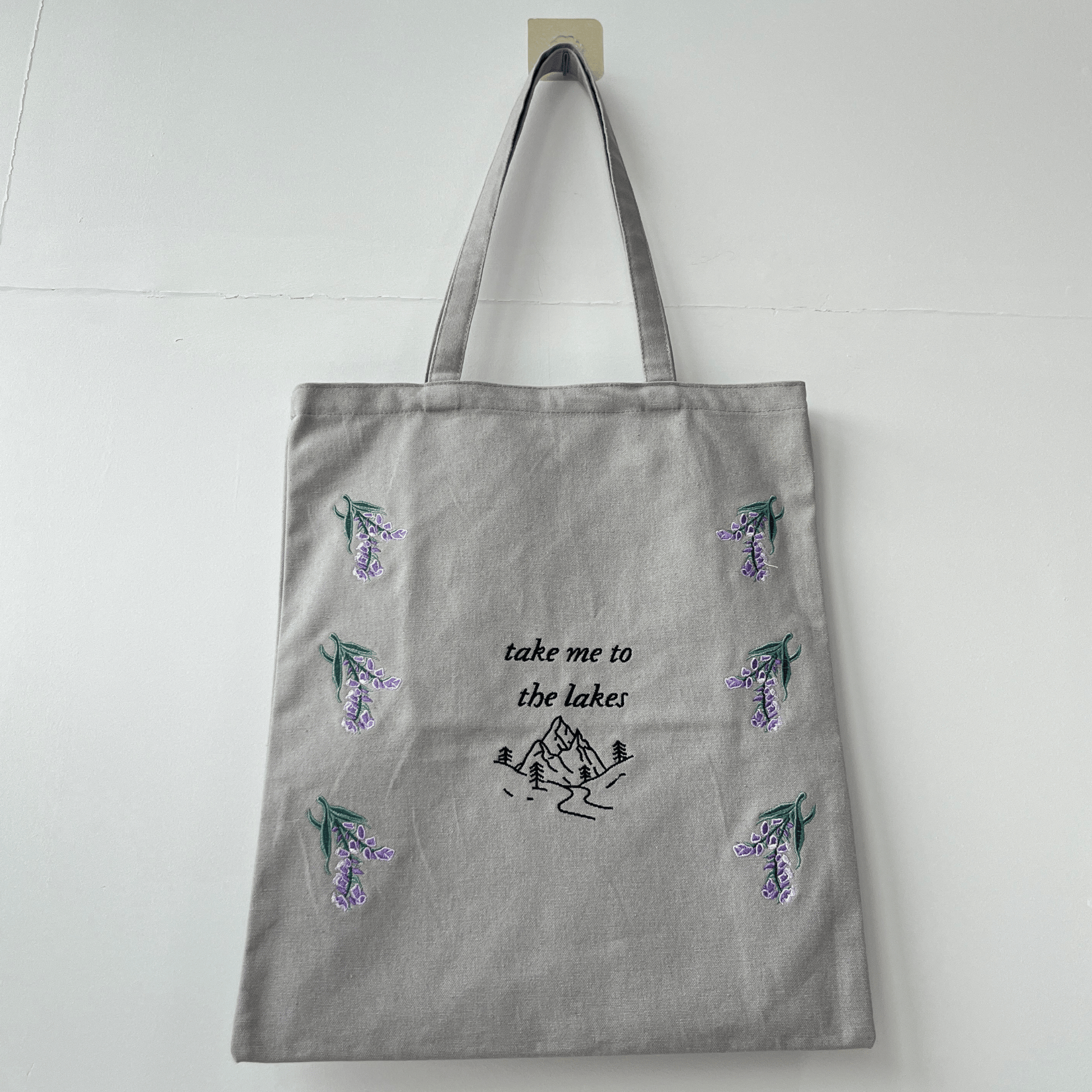 Gray tote bag with nature-themed designs and text on a white background