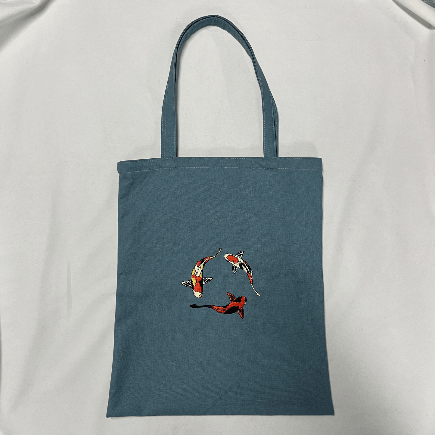 Blue tote bag with fish design on a white background