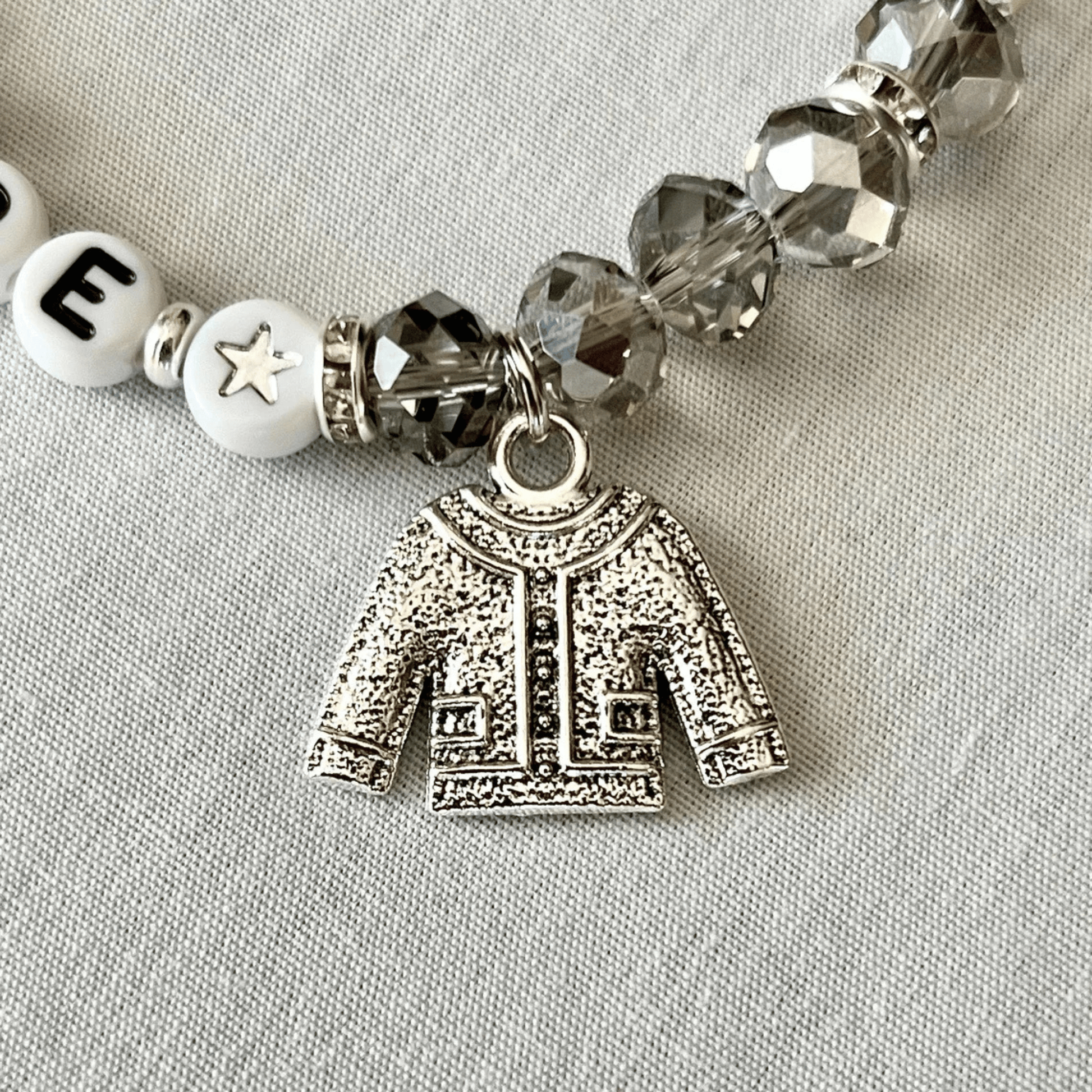 Bracelet with silver cardigan charm and beads on a light gray background