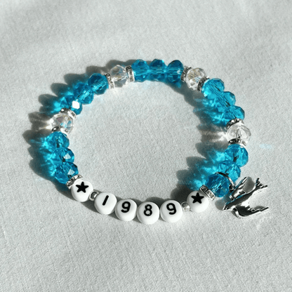 Blue beaded bracelet with '1989' on a light gray background