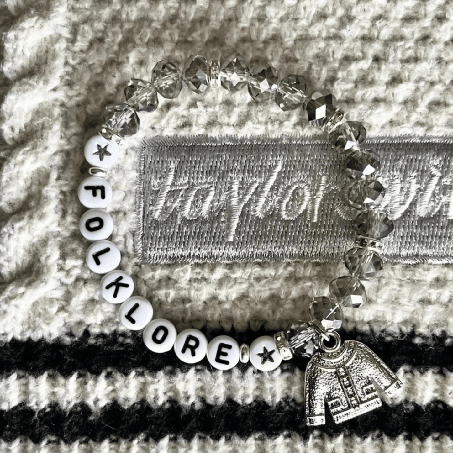 Bracelet with 'FOLKLORE' beads and a small tag on a textured surface