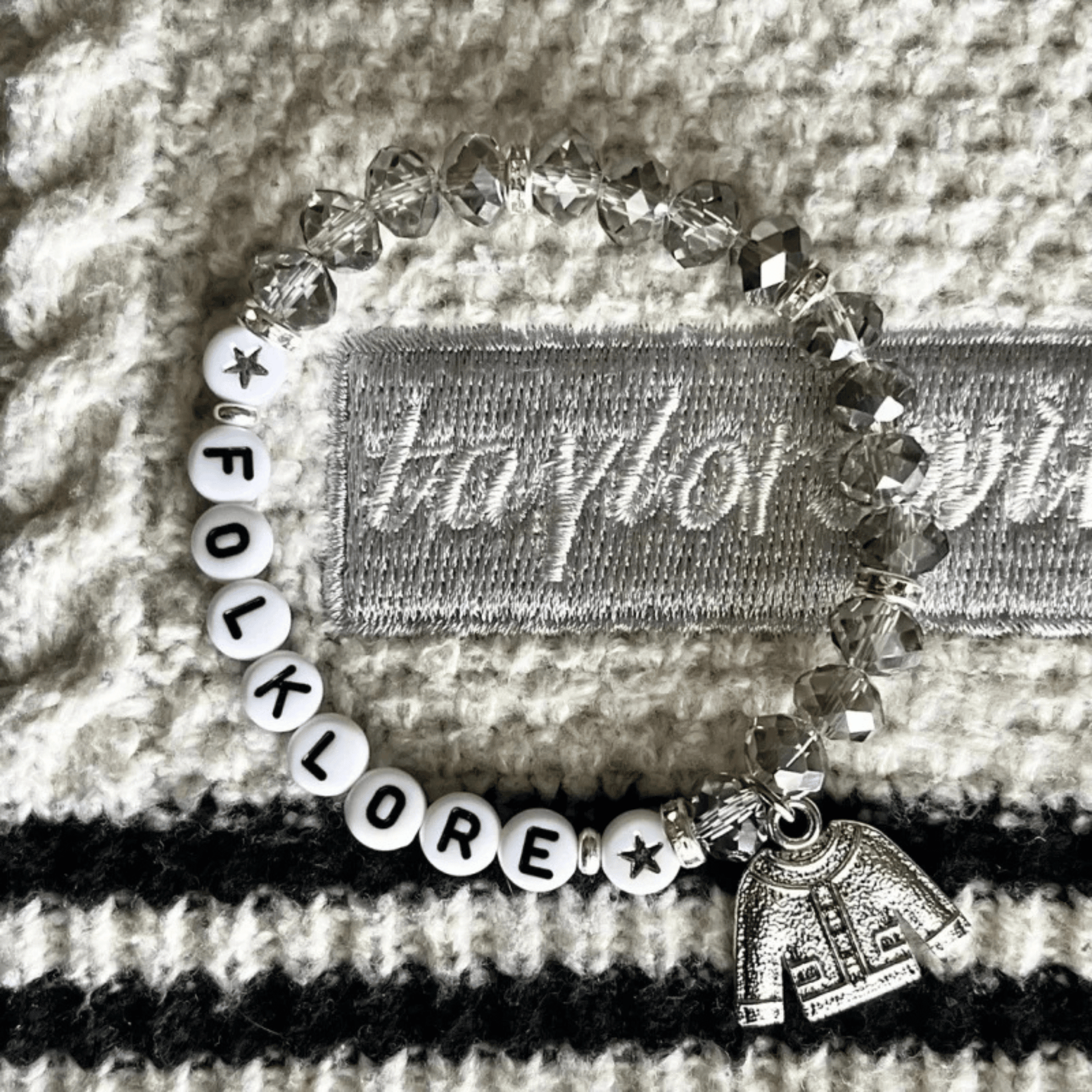 Bracelet with 'FOLKLORE' beads and a small tag on a textured surface
