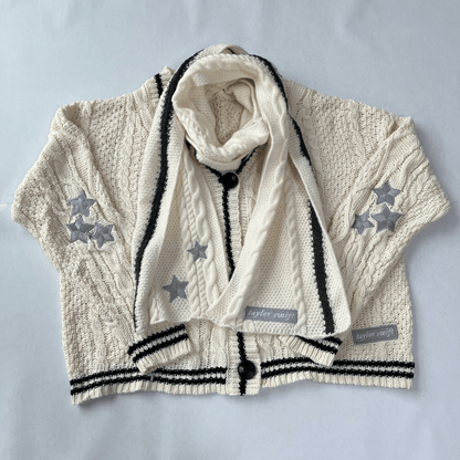 Children's cable knit cardigan with star patterns and a matching scarf on a light gray background.