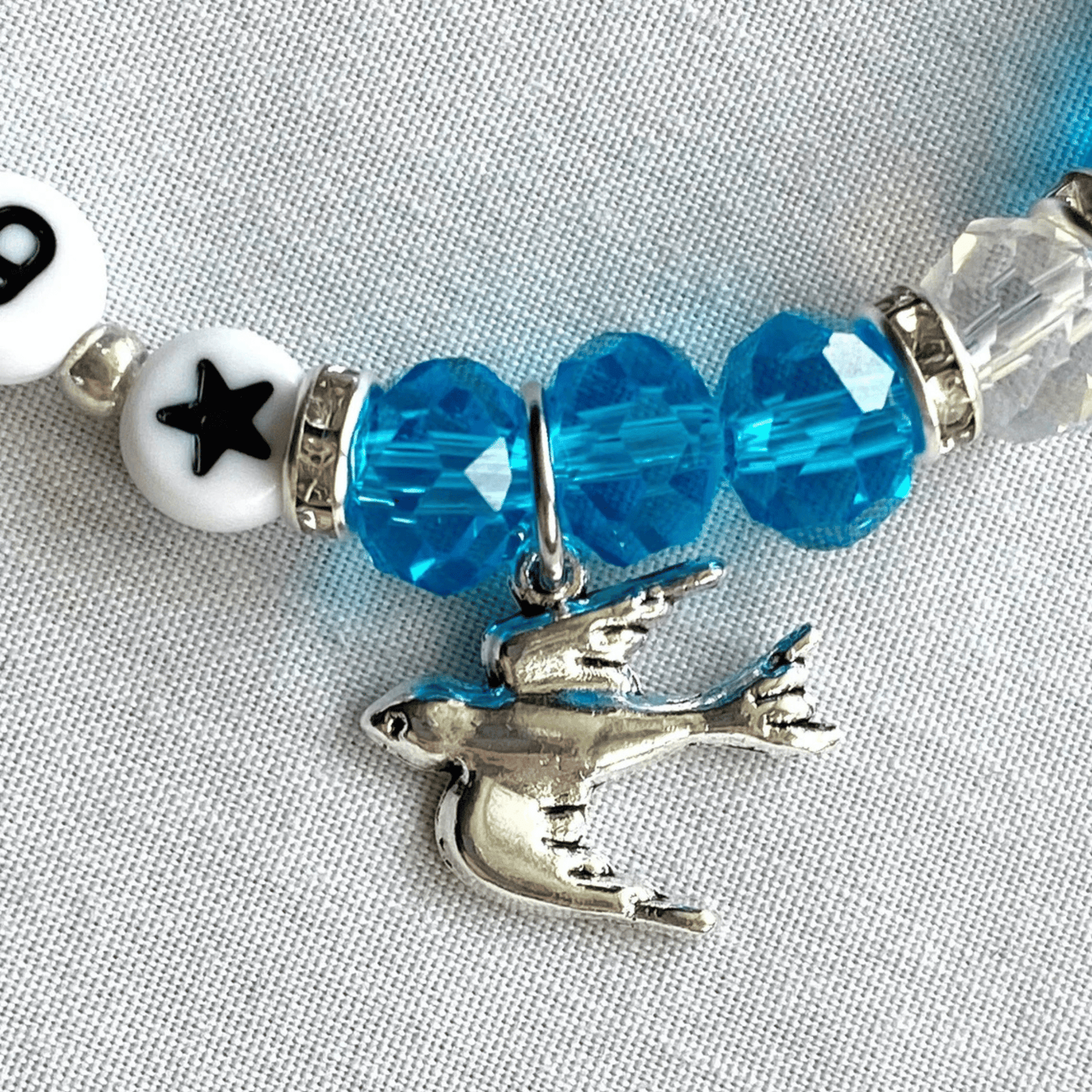 Bracelet with blue beads and a silver shark charm on a gray background