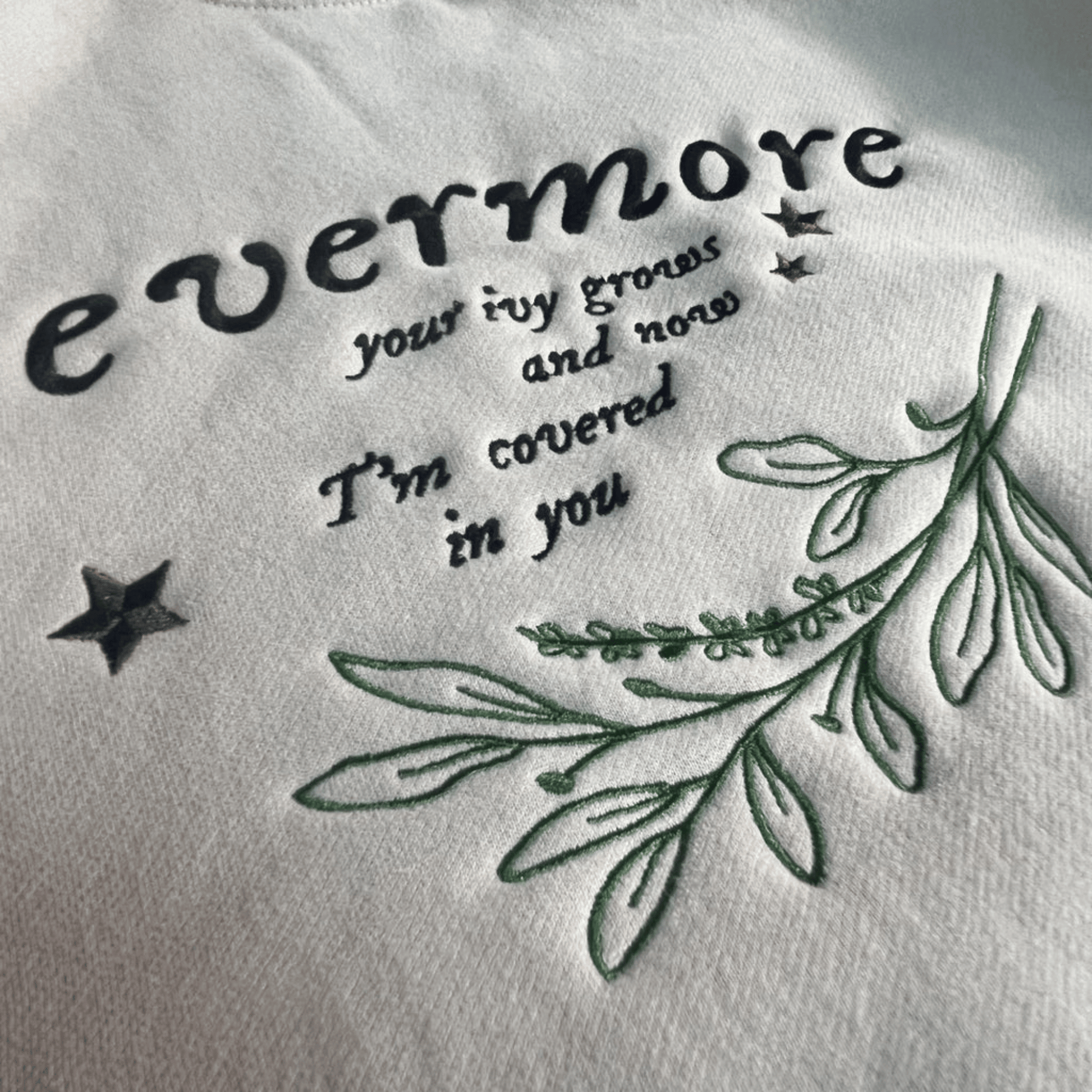 Embroidered text and leaves on a white fabric background