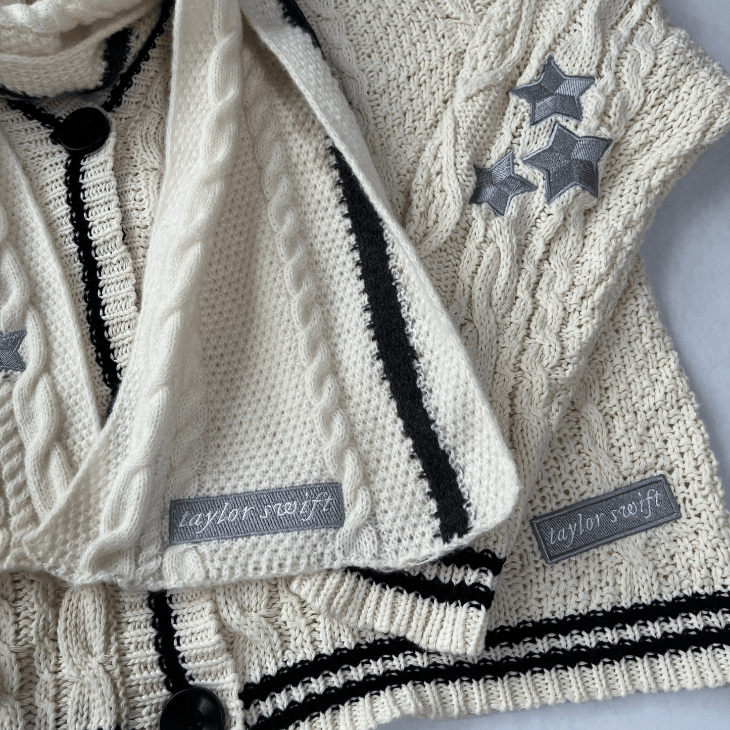 Knitted sweater with star patterns and 'Taylor Swift' labels on a light background