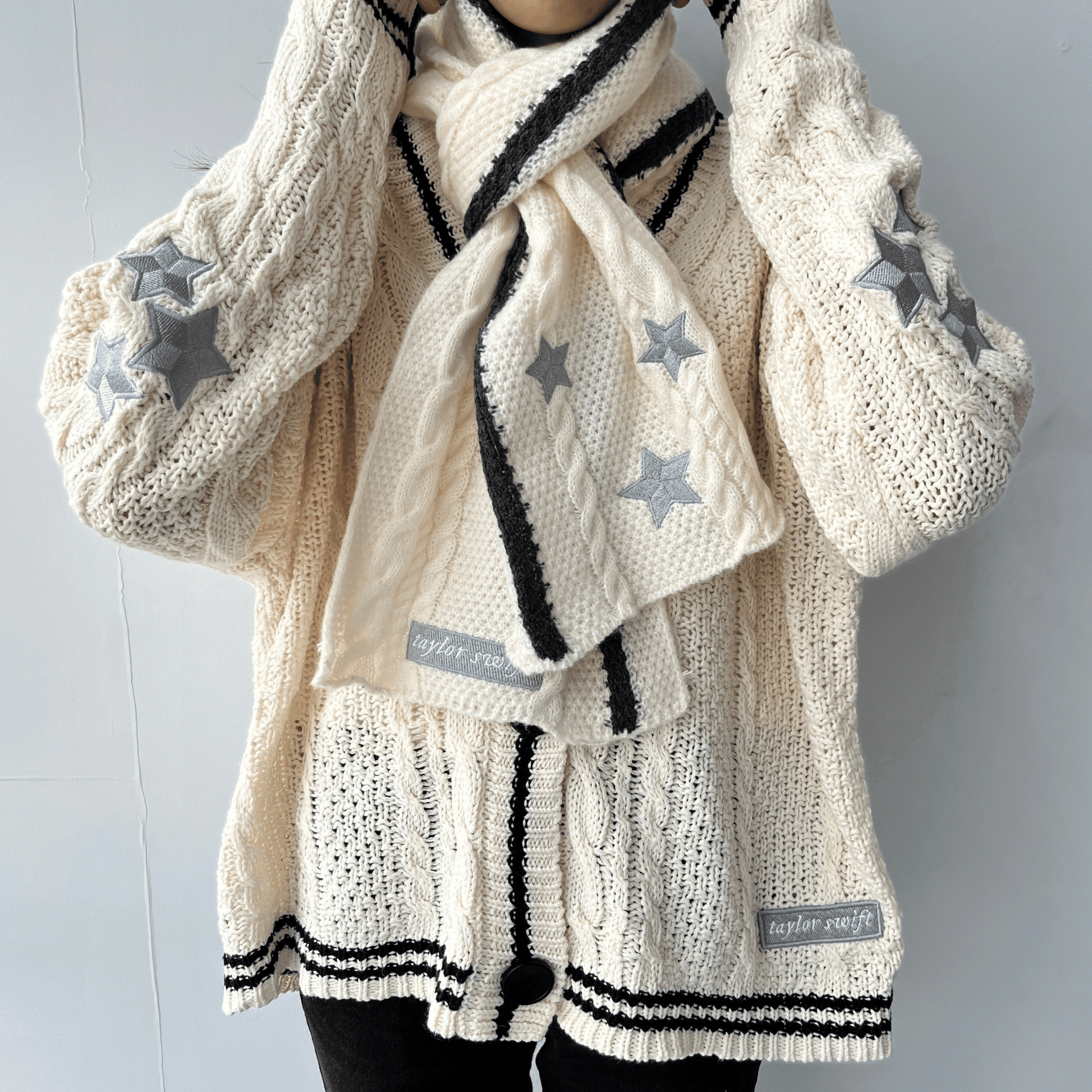 Knitted cardigan with star patterns and a matching scarf on a plain background