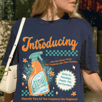 Person wearing a blue t-shirt with a colorful graphic and text, holding a beige handbag.