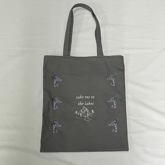 Gray tote bag with nature-themed designs and text on a light gray background