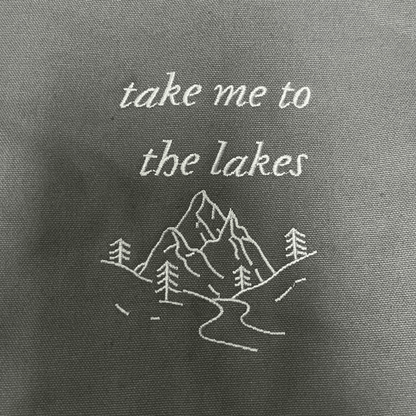 Embroidered text and mountain design on a gray fabric background