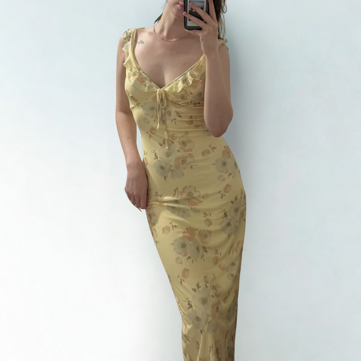 Person wearing a yellow floral dress against a white background