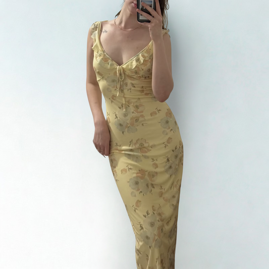Person wearing a yellow floral dress against a white background