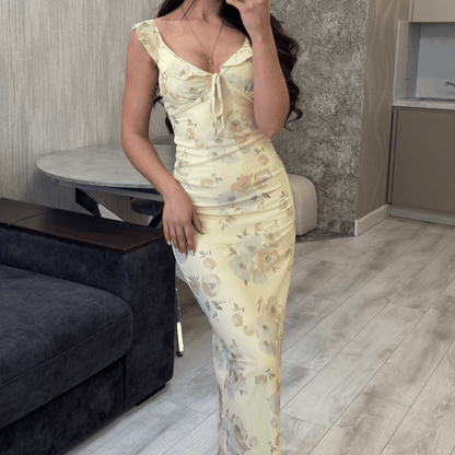 Woman in a floral dress standing in a room with a couch and table.