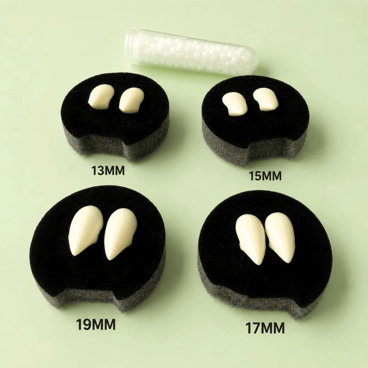 Four black circular foam pieces showing different tooth-size options labeled 13MM, 15MM, 17MM, and 19MM, with a clear tube of small white teeth above on a pale green background.