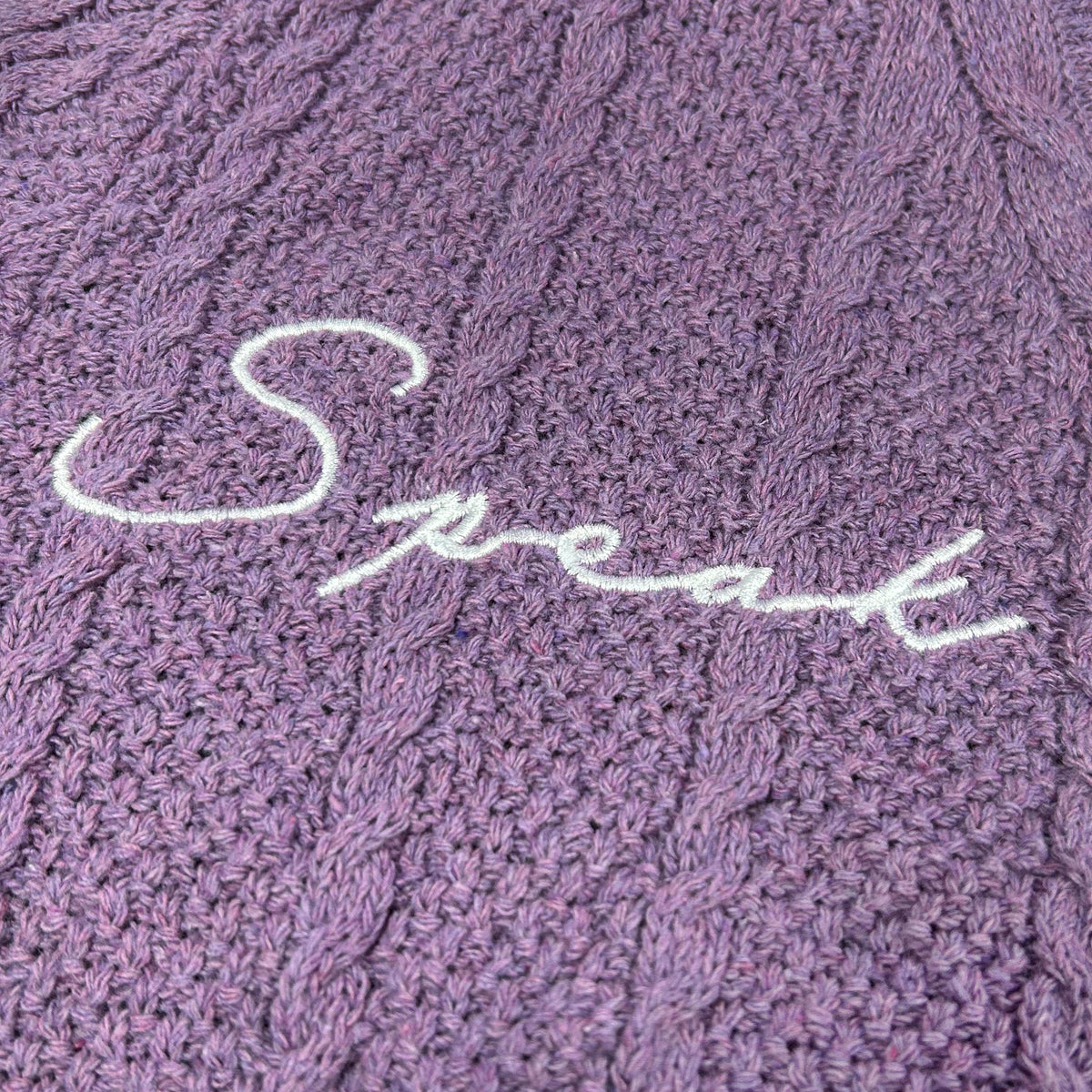 Purple eras crop cardigan close up of white script embroidery on front panel