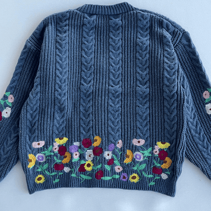 Blue knitted sweater with floral embroidery on a white background