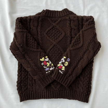 Brown knitted sweater with floral embroidery on a white background
