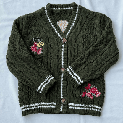 Green knitted cardigan with floral embroidery on a white background