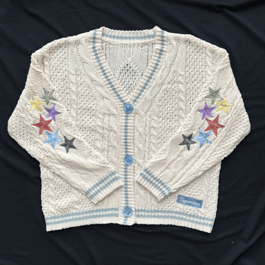 White knitted cardigan with colorful star designs on a dark background