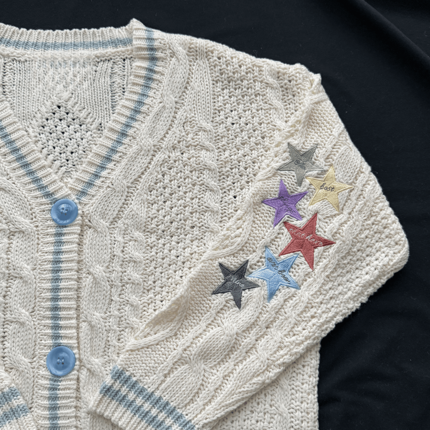 Knitted cardigan with colorful star patches on a dark background