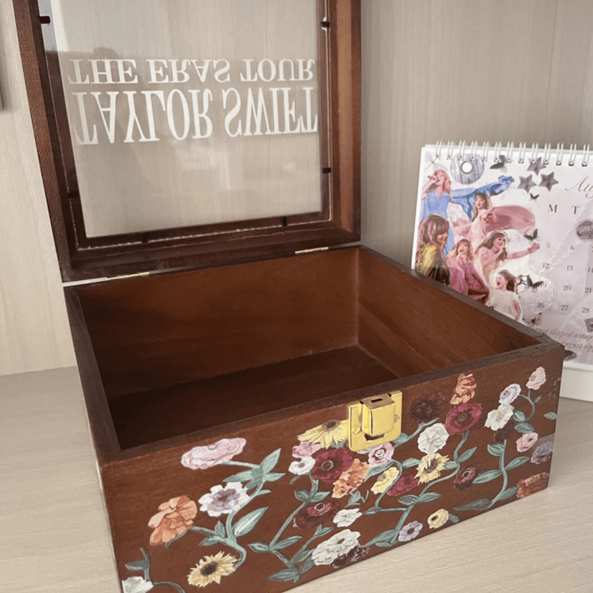 Taylor Swift Wooden Storage Box with floral Eras Piano design, next to a calendar on a wooden floor - Shoptown Boutique