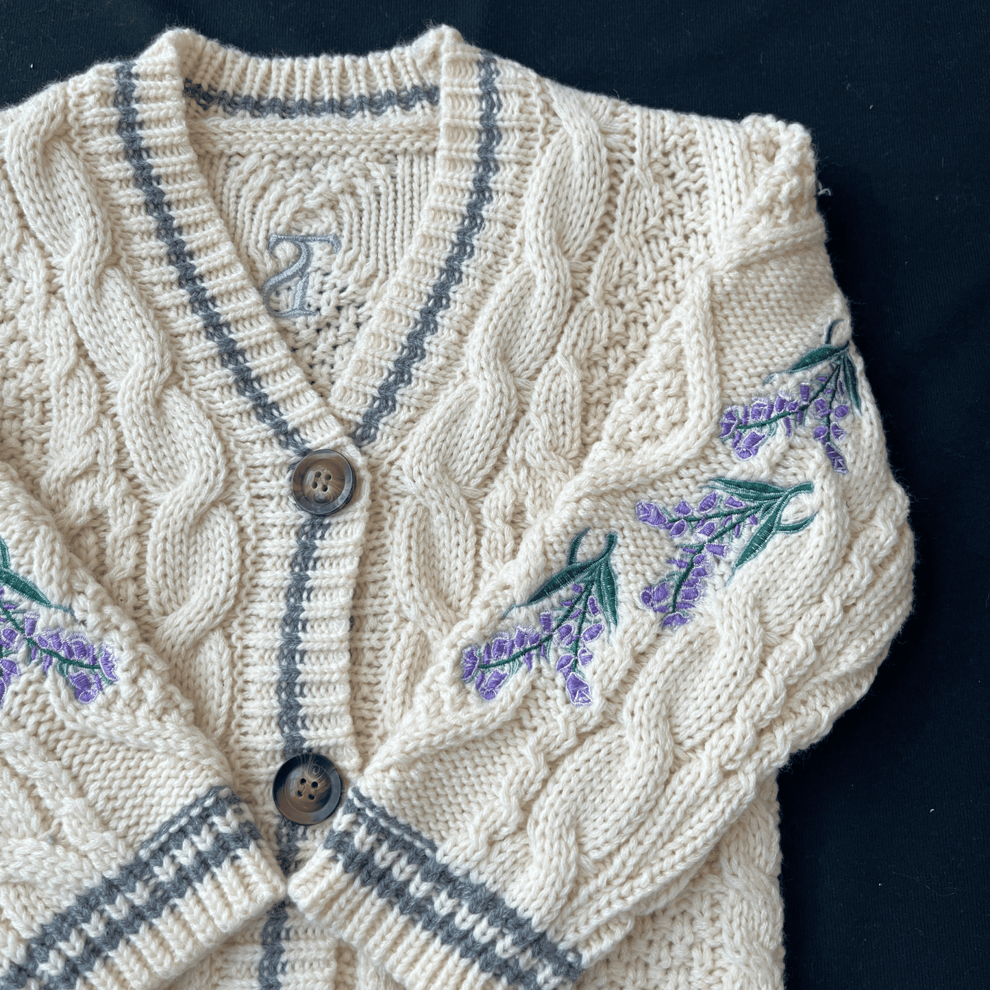 Knitted cardigan with embroidered lavender flowers on a dark background