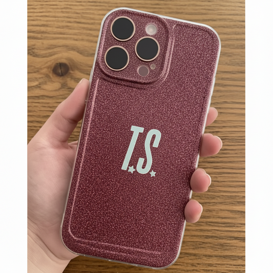 Phone case with 'T.S.' initials held by a hand on a wooden surface